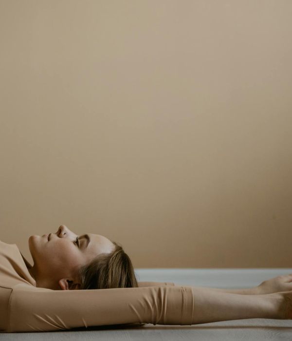 Woman in a calming yoga pose against a soft beige background.